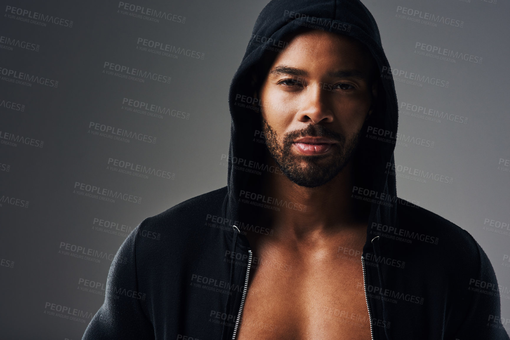 Buy stock photo Portrait of a handsome young man wearing a hoodie posing against a grey background