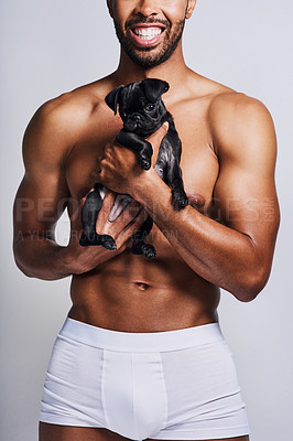 Buy stock photo Cropped shot of an unrecognizable man posing with his adorable puppy against a grey background