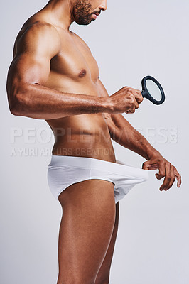 Buy stock photo Cropped shot of an unrecognizable man in underwear checking his pubic area against a grey background