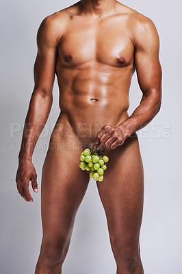 Buy stock photo Shot of an unrecognizable naked man posing with a bunch of grapes covering his genital area against a grey background