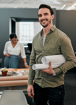 Buy stock photo Shot of a young architect holding rolled up blueprints in an office