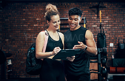 Buy stock photo Shot of a sporty young woman talking to a fitness trainer at the gym