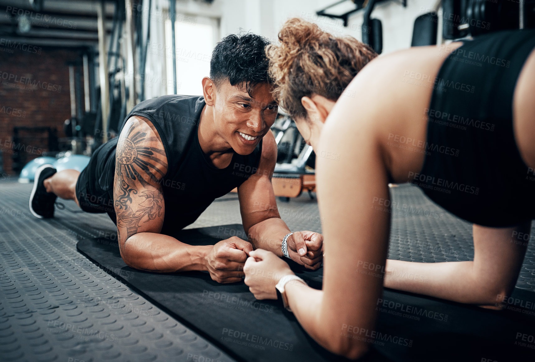 Buy stock photo Shot of two sporty young people working out together at the gym