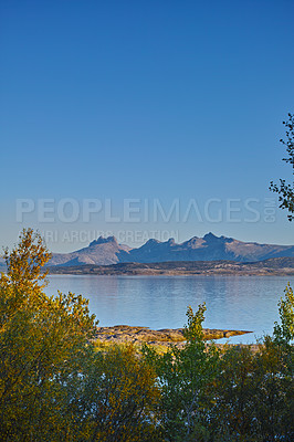 Buy stock photo A sea landscape near a mountain with a blue sky background and copy space. Vibrant outdoors by the ocean or beach with lush green plants or nature hills and copyspace on a summer day