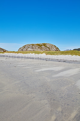 Buy stock photo Scenic view of an ocean beach with boulders or rocks in the background. Low tide sea waves washing onto shoreline with blue sky and copy space. Overseas travel and peaceful tourism destination abroad