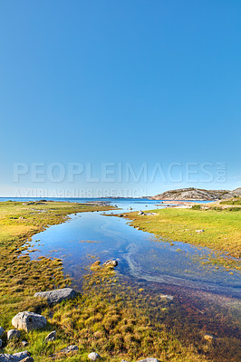 Buy stock photo Scenic view of a river flowing through a swamp and leading to the ocean in Norway. Landscape view of blue copy space sky and a marshland. Overflow of water pollution and oil deposits entering the sea