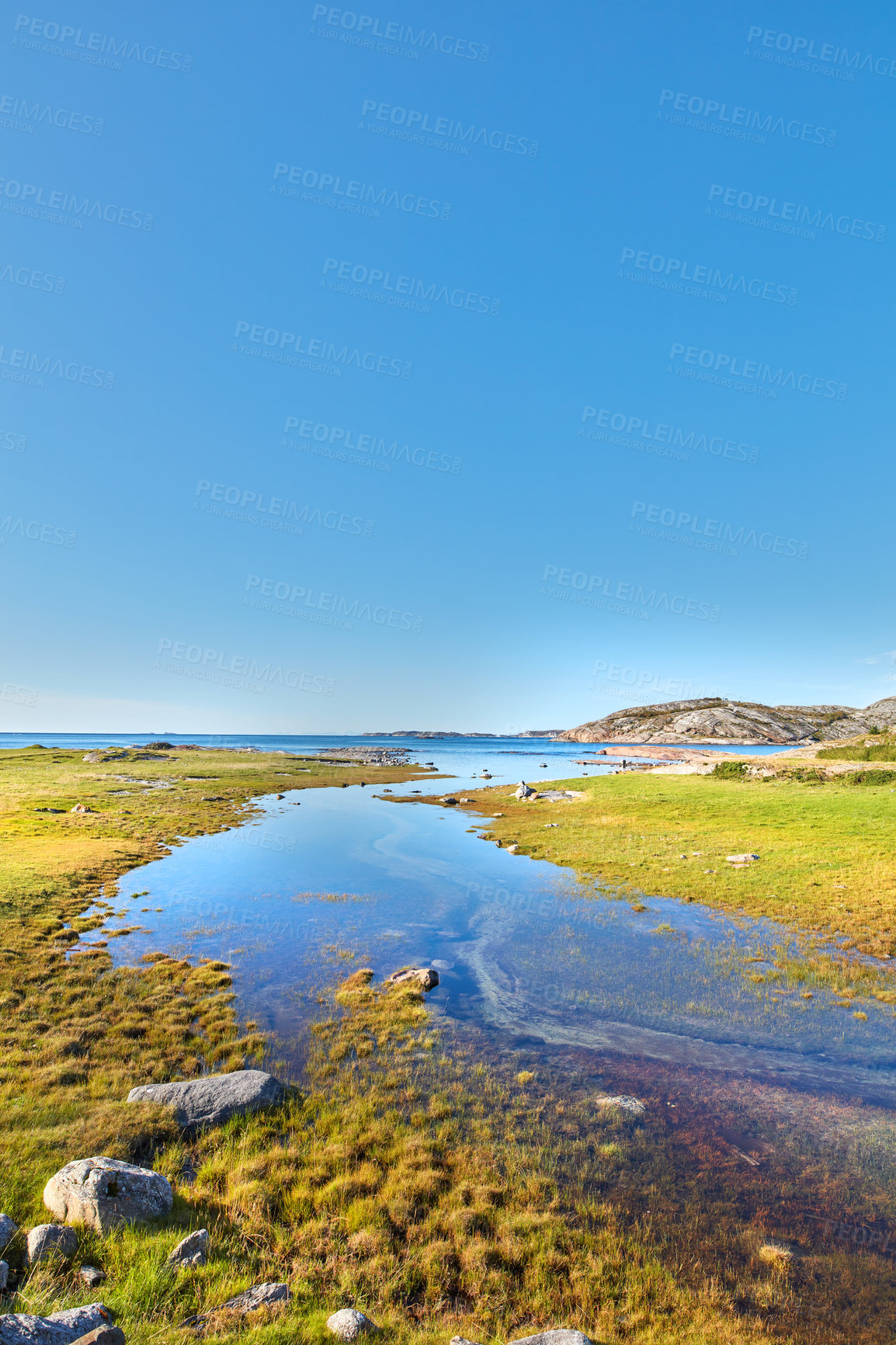 Buy stock photo Scenic view of a river flowing through a swamp and leading to the ocean in Norway. Landscape view of blue copy space sky and a marshland. Overflow of water pollution and oil deposits entering the sea