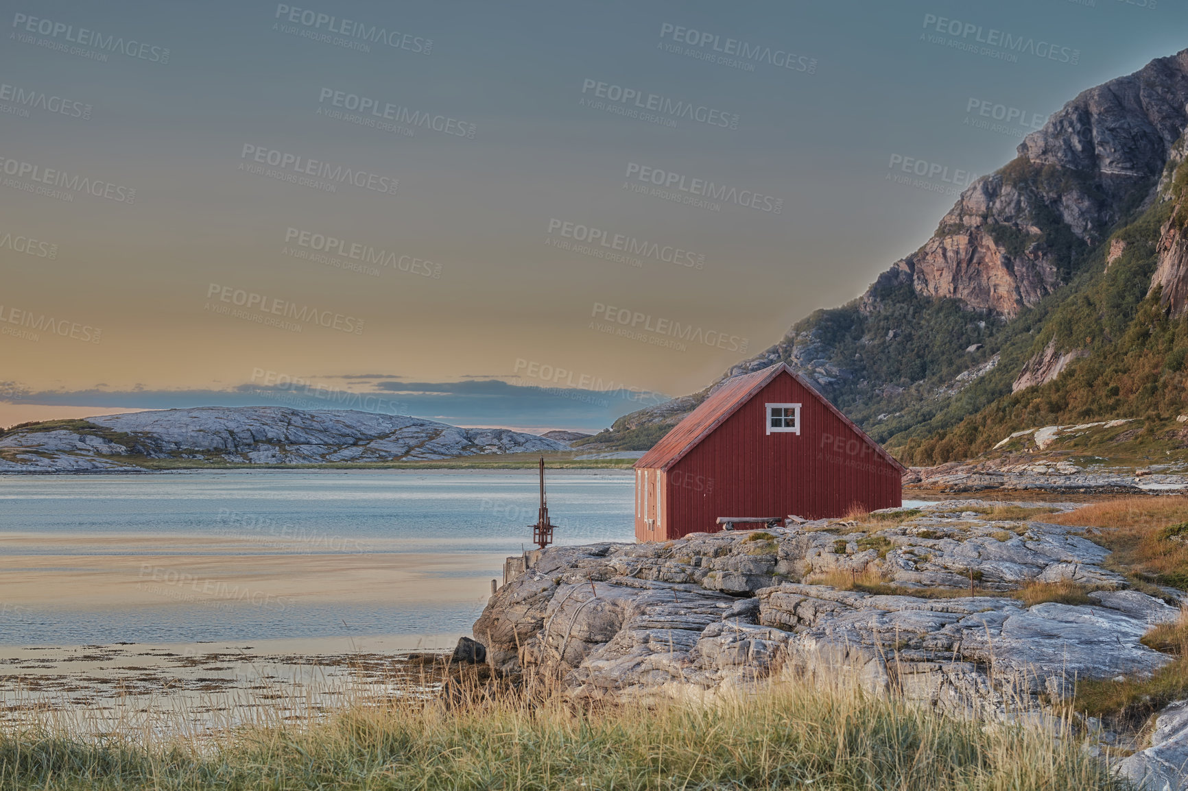 Buy stock photo Scenic view of abandoned lake house or cabin in a remote and rocky countryside. Natural wilderness around a small bay of water in Norway. Landscape and seascape of an ocean or sea with blue sky