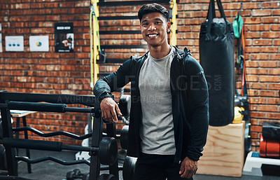 Buy stock photo Cropped portrait of a handsome young male fitness instructor smiling while standing in a gym