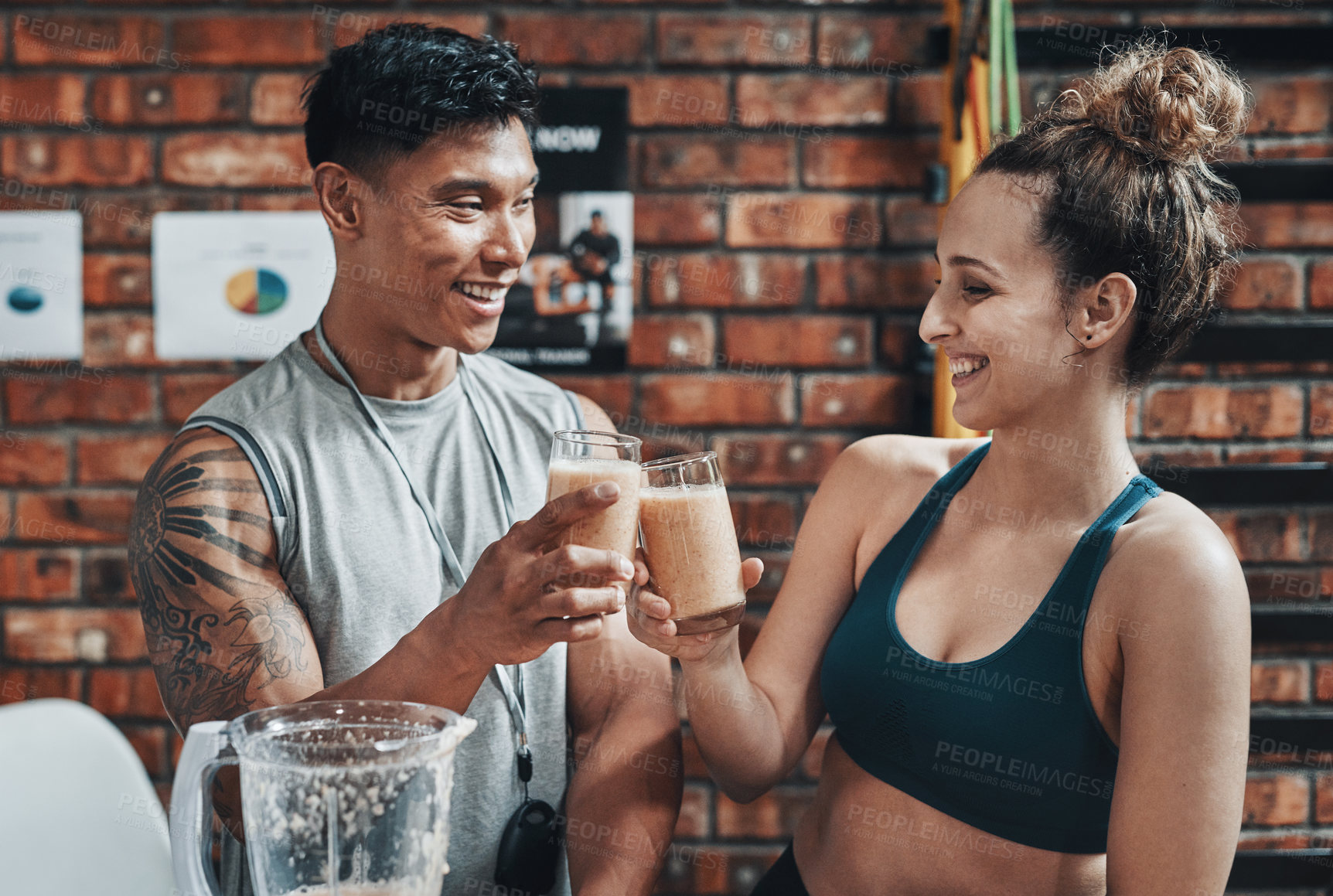 Buy stock photo Cropped shot of two young sportspeople making a toast with milkshakes while working in a gym