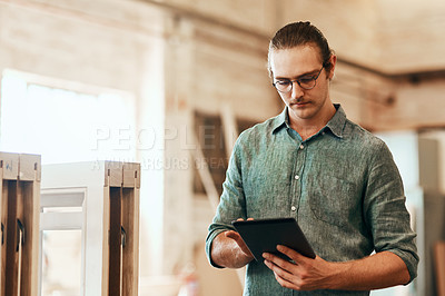 Buy stock photo Cropped shot of a young carpenter using a digital tablet while working inside his workshop