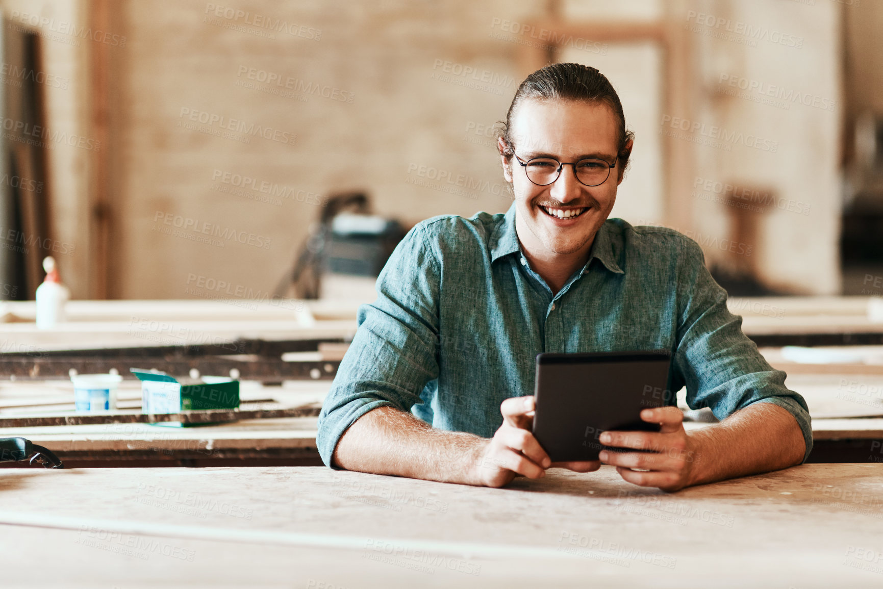 Buy stock photo Portrait of a young carpenter using a digital tablet while working inside his workshop