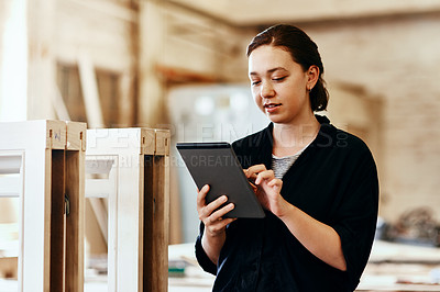 Buy stock photo Cropped shot of a young female carpenter using a digital tablet while working inside her workshop