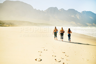 Buy stock photo Rearview shot of three young woman looking for a spot on the beach to practice yoga