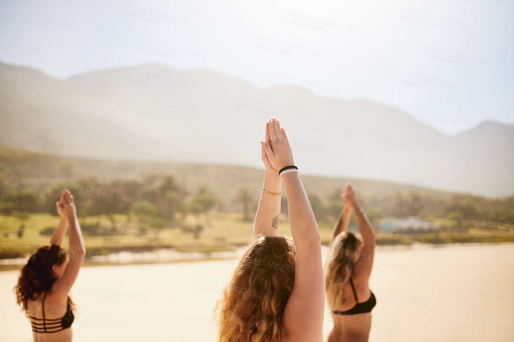 Buy stock photo Shot of three young women practising yoga on the beach