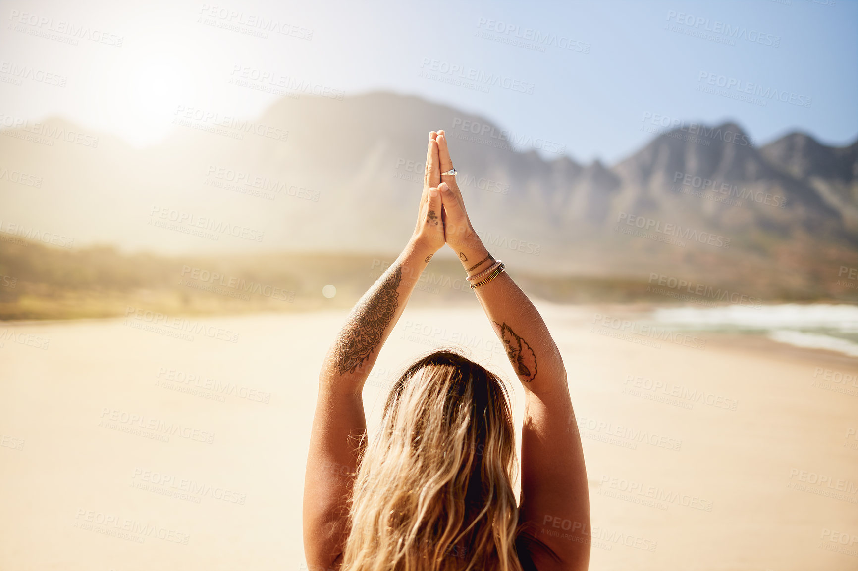 Buy stock photo Rearview shot of a young woman practising yoga on the beach