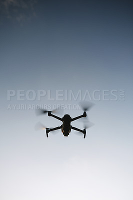 Buy stock photo Low angle shot of a drone flying high in the sky