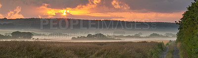 Buy stock photo Landscape view of fog over remote field with copy space at sunset. Mist covering a vast expanse of countryside meadow in Germany at dawn. Smoke from wildfire or bush fires rolling over nature reserve