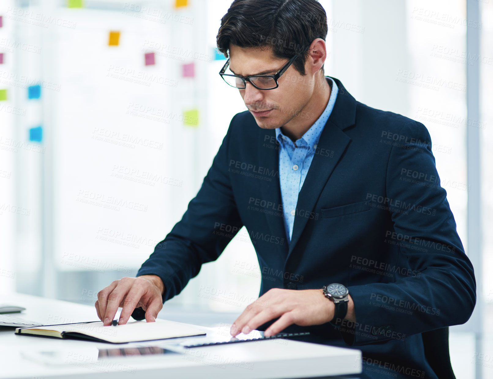 Buy stock photo Shot of a young businessman using a notebook in an office