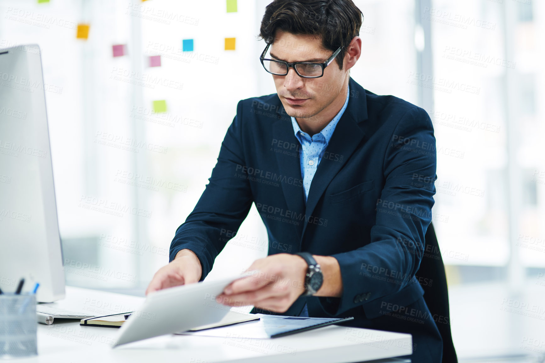 Buy stock photo Shot of a young businessman using a digital tablet in an office