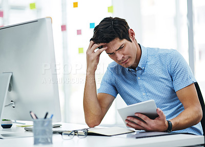 Buy stock photo Shot of a young businessman looking confused while working in an office