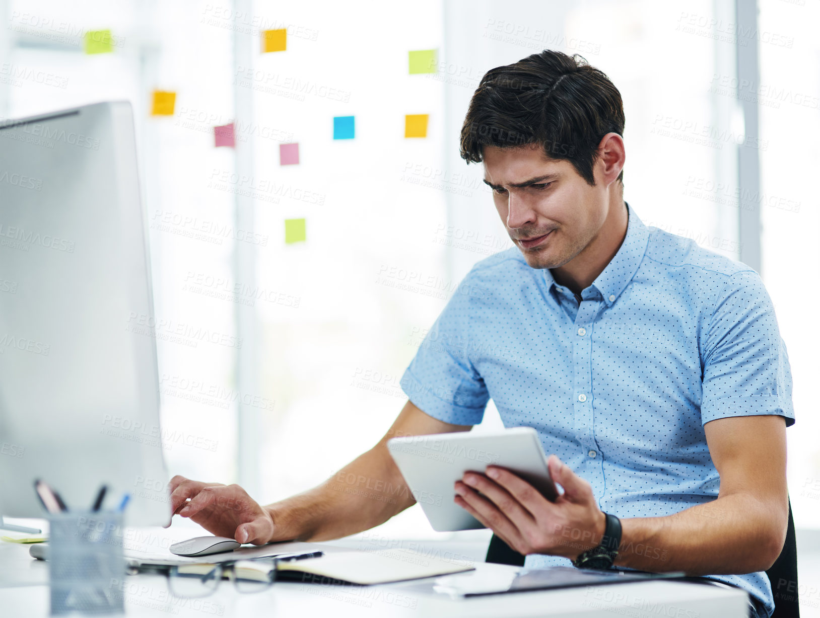 Buy stock photo Shot of a young businessman looking confused while working in an office