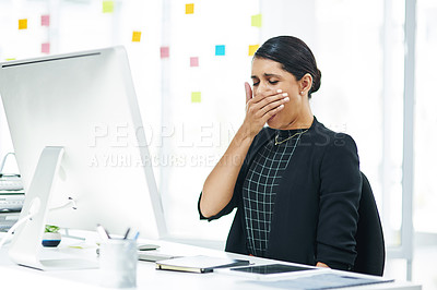 Buy stock photo Shot of a young businesswoman yawning while working in an office