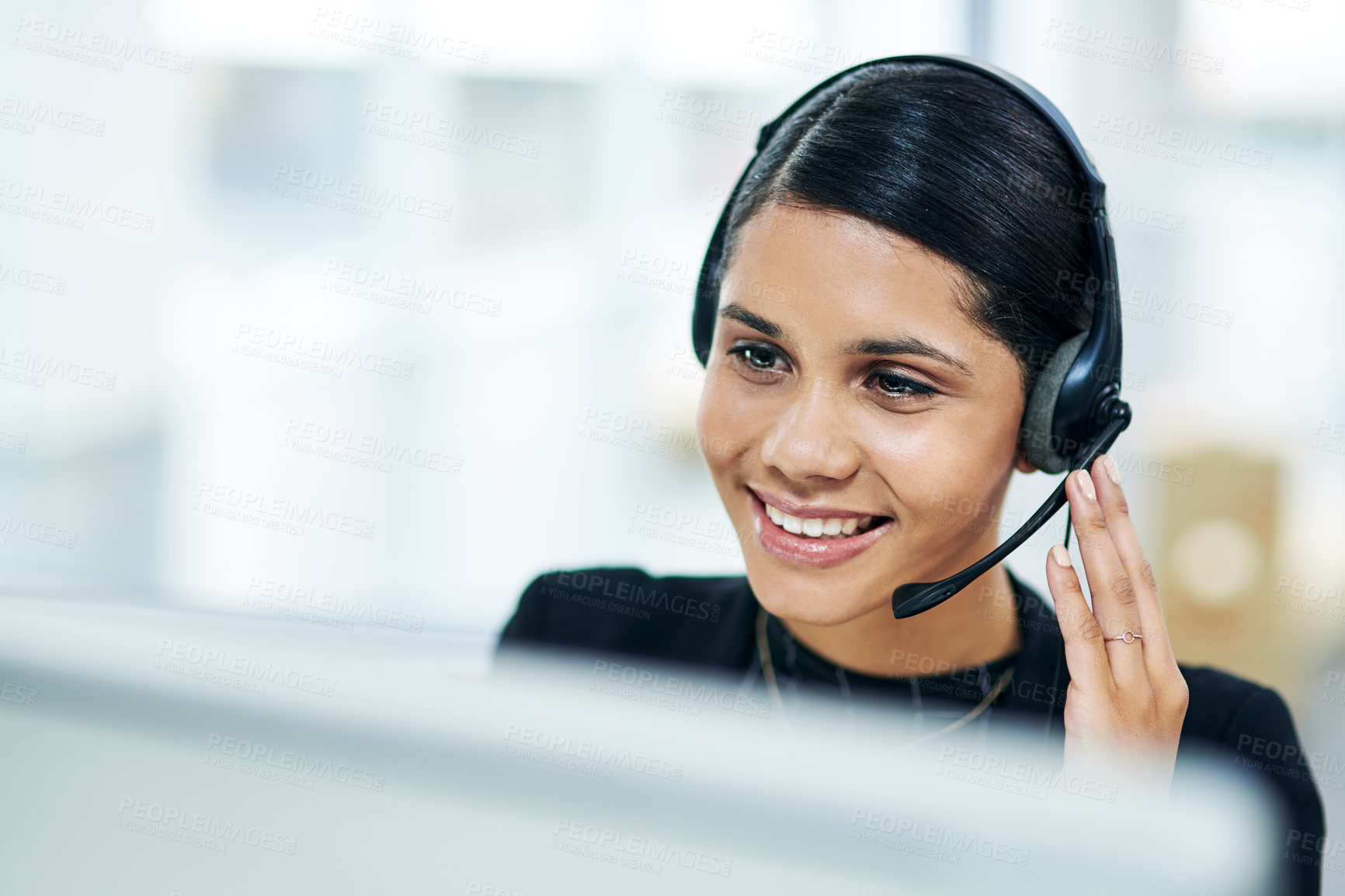 Buy stock photo Shot of a young businesswoman using a headset while working on a computer in an office