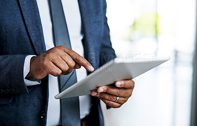Buy stock photo Cropped shot of an unrecognizable businessman using a digital tablet while standing in a modern office