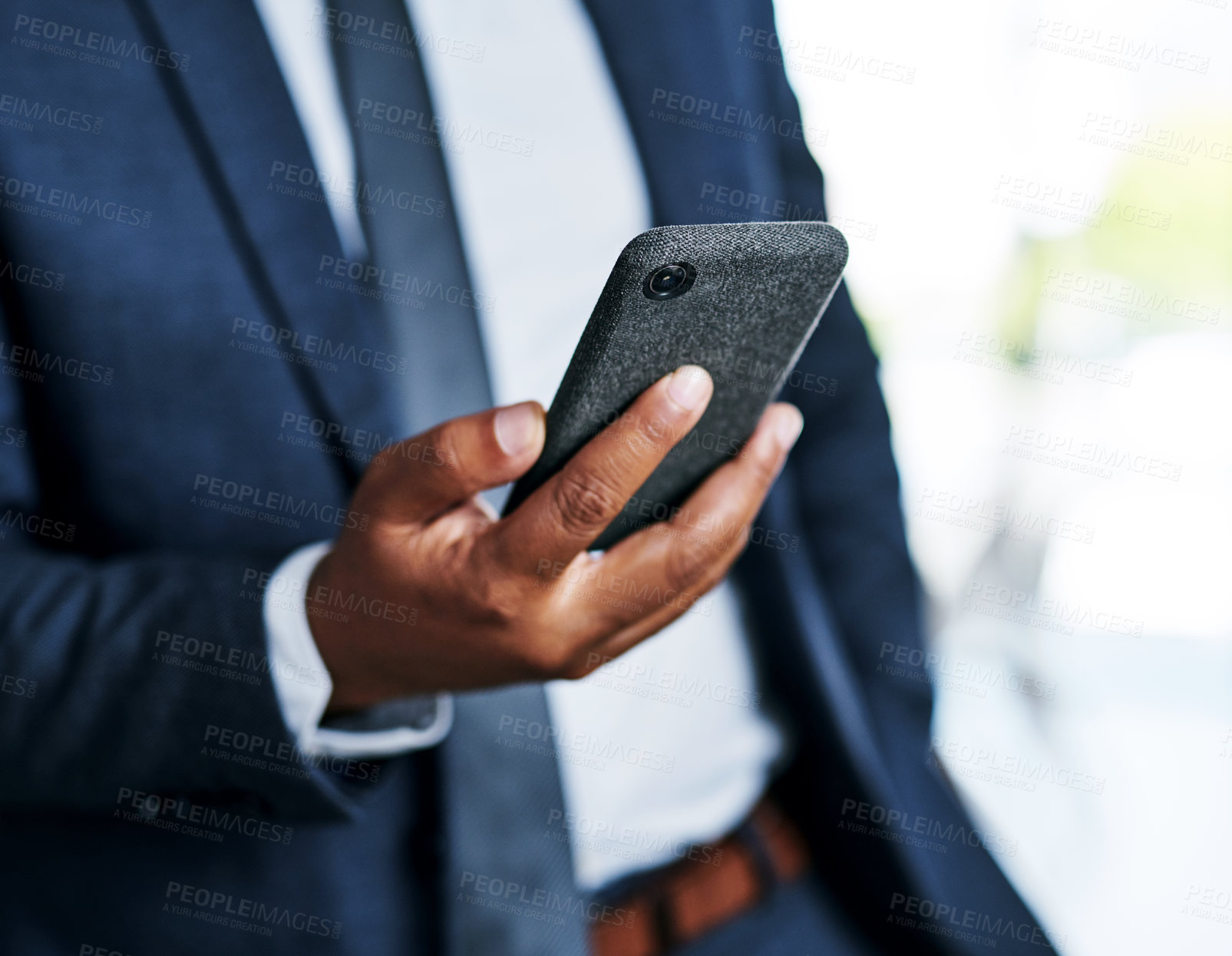 Buy stock photo Cropped shot of an unrecognizable businessman using a smartphone while standing in a modern office