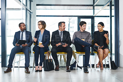 Buy stock photo Full length shot of a diverse group of businesspeople conversing with each other while sitting in line for an interview in a modern office