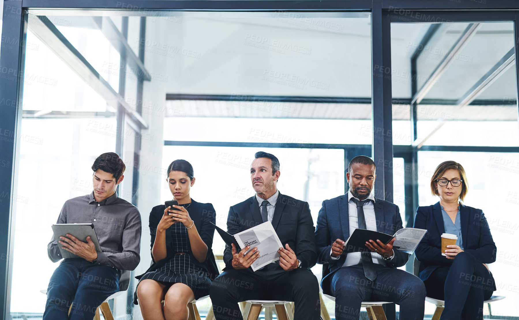 Buy stock photo Cropped shot of a diverse group of businesspeople sitting in line for an interview in a modern office