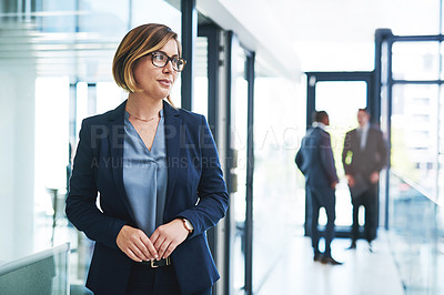 Buy stock photo Cropped shot of an attractive young businesswoman looking thoughtful in a modern office with her colleagues in the background