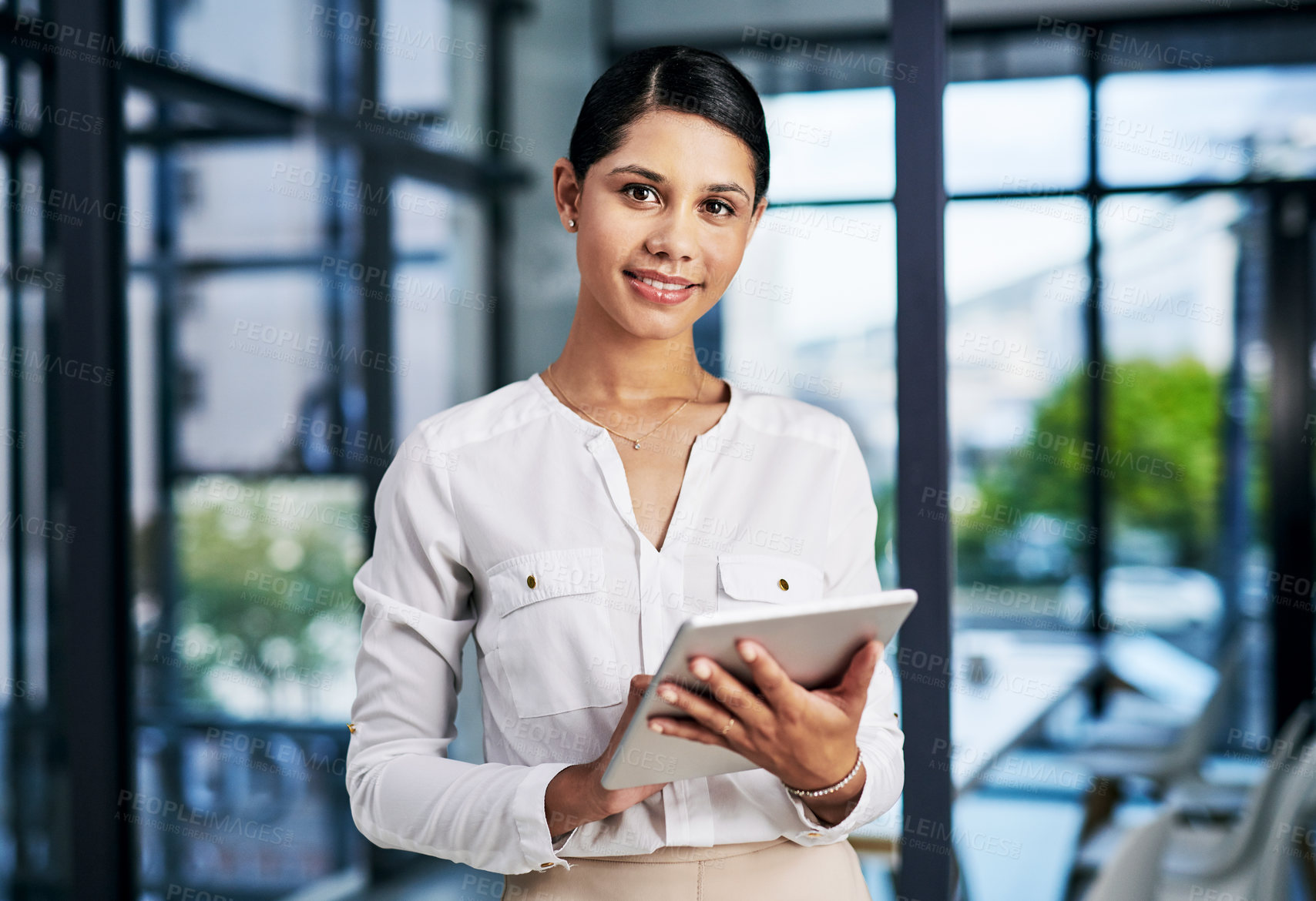 Buy stock photo Cropped portrait of an attractive young businesswoman smiling while using a digital tablet in a modern office