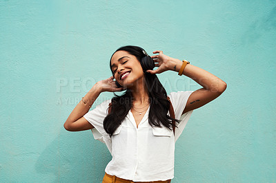Buy stock photo Cropped shot of an attractive young woman standing alone and dancing while listening to music against a blue background