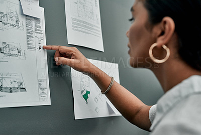 Buy stock photo Closeup shot of an architect working with blueprints on a wall in an office