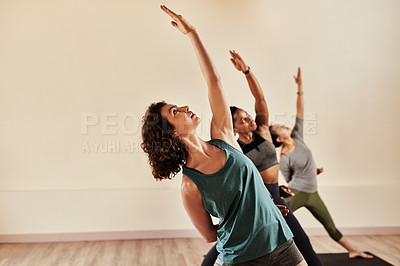 Buy stock photo Shot of a group of young men and women practicing yoga in a fitness class