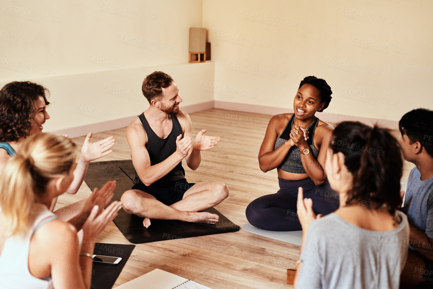 Buy stock photo Shot of a group of young men and women clapping during a yoga class