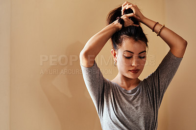 Buy stock photo Shot of a young woman tying up her hair in preparation for a yoga session