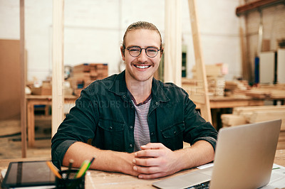 Buy stock photo Portrait of a handsome young carpenter working on a laptop inside his workshop