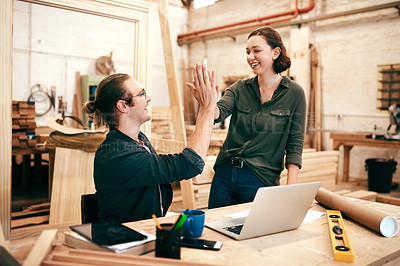 Buy stock photo Cropped shot of two young carpenters joining for a high five while working together inside their workshop