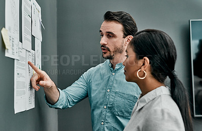 Buy stock photo Shot of two architects working with blueprints on a wall in an office