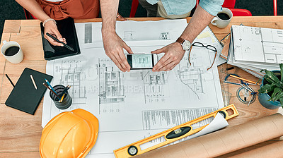 Buy stock photo Closeup shot of two unrecognisable architects using a cellphone to take photos of blueprints in an office