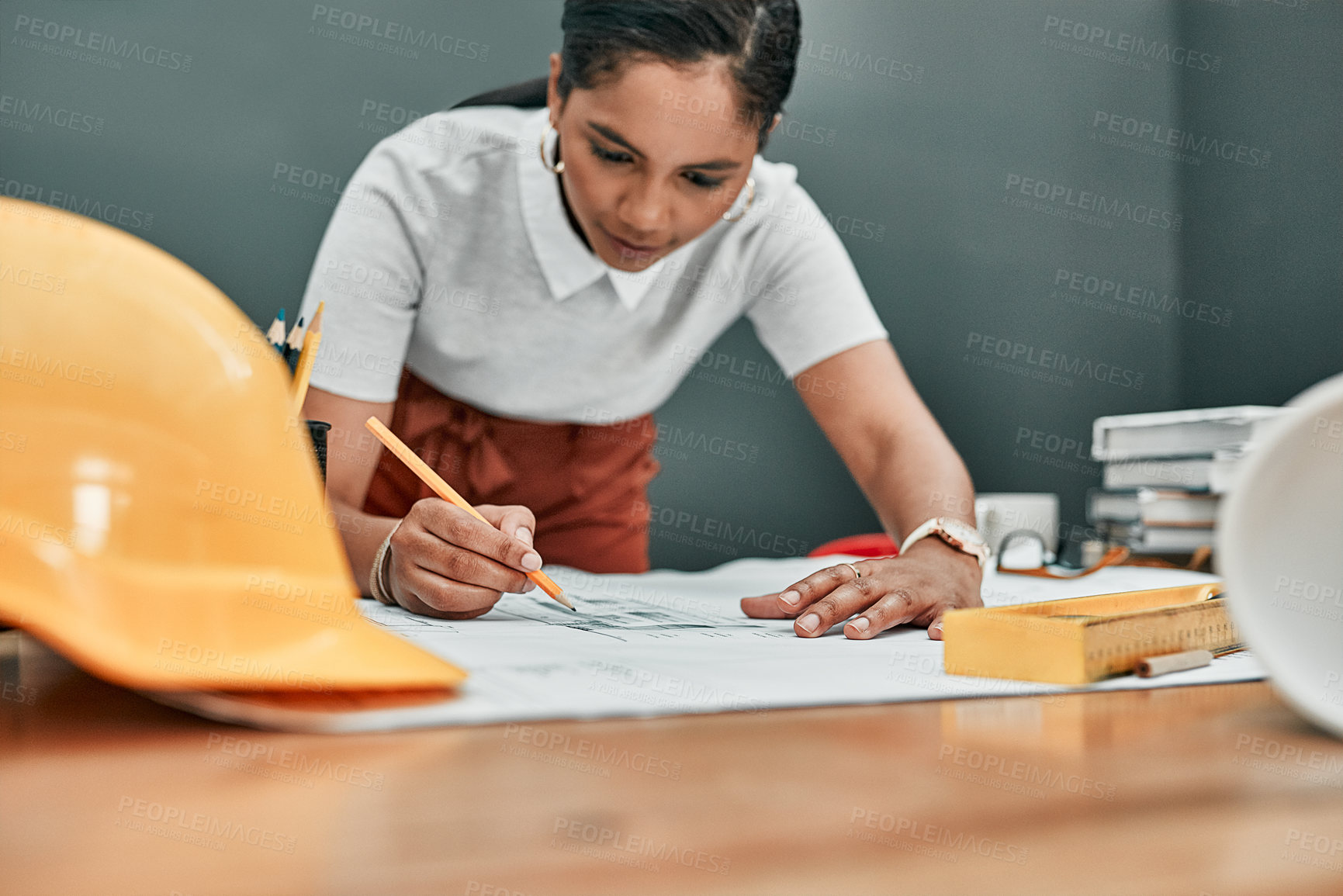 Buy stock photo Shot of a young architect working with blueprints in an office