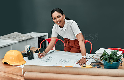 Buy stock photo Portrait of a young architect working with blueprints in an office