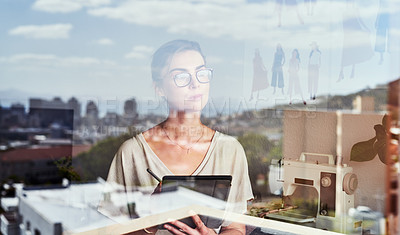 Buy stock photo Shot of a fashion designer looking thoughtfully out her office window