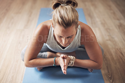 Buy stock photo Cropped shot of an attractive young woman sitting alone on a yoga mat and holding a yoga pose