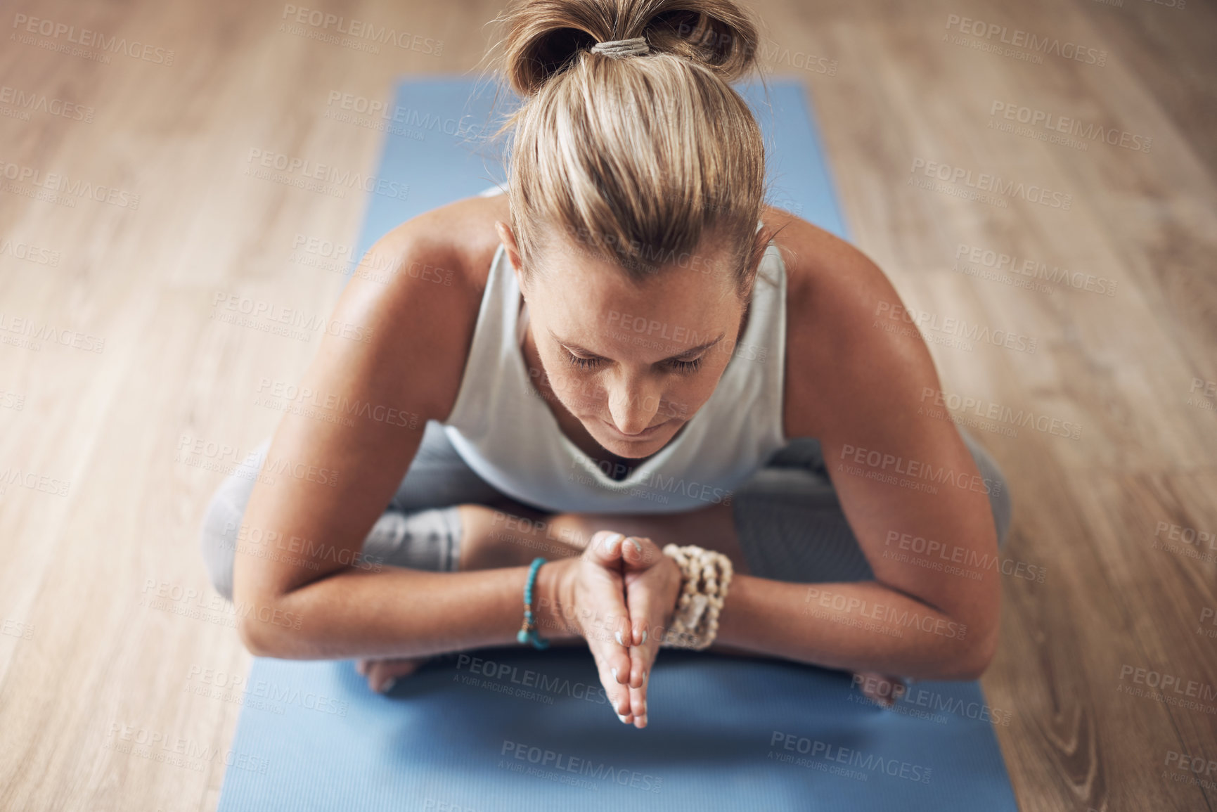 Buy stock photo Cropped shot of an attractive young woman sitting alone on a yoga mat and holding a yoga pose