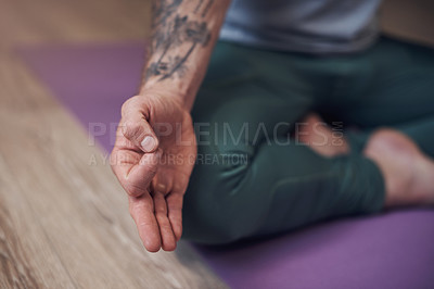 Buy stock photo Cropped shot of an unrecognizable man sitting indoors alone and meditating with his hand in a gyan mudra