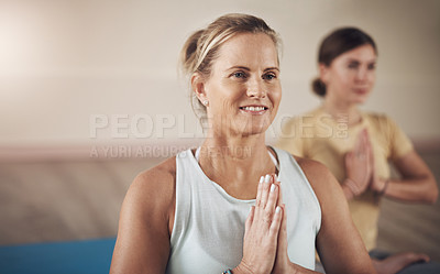 Buy stock photo Cropped shot of two young women sitting together and meditating with their palms together after an indoor yoga session